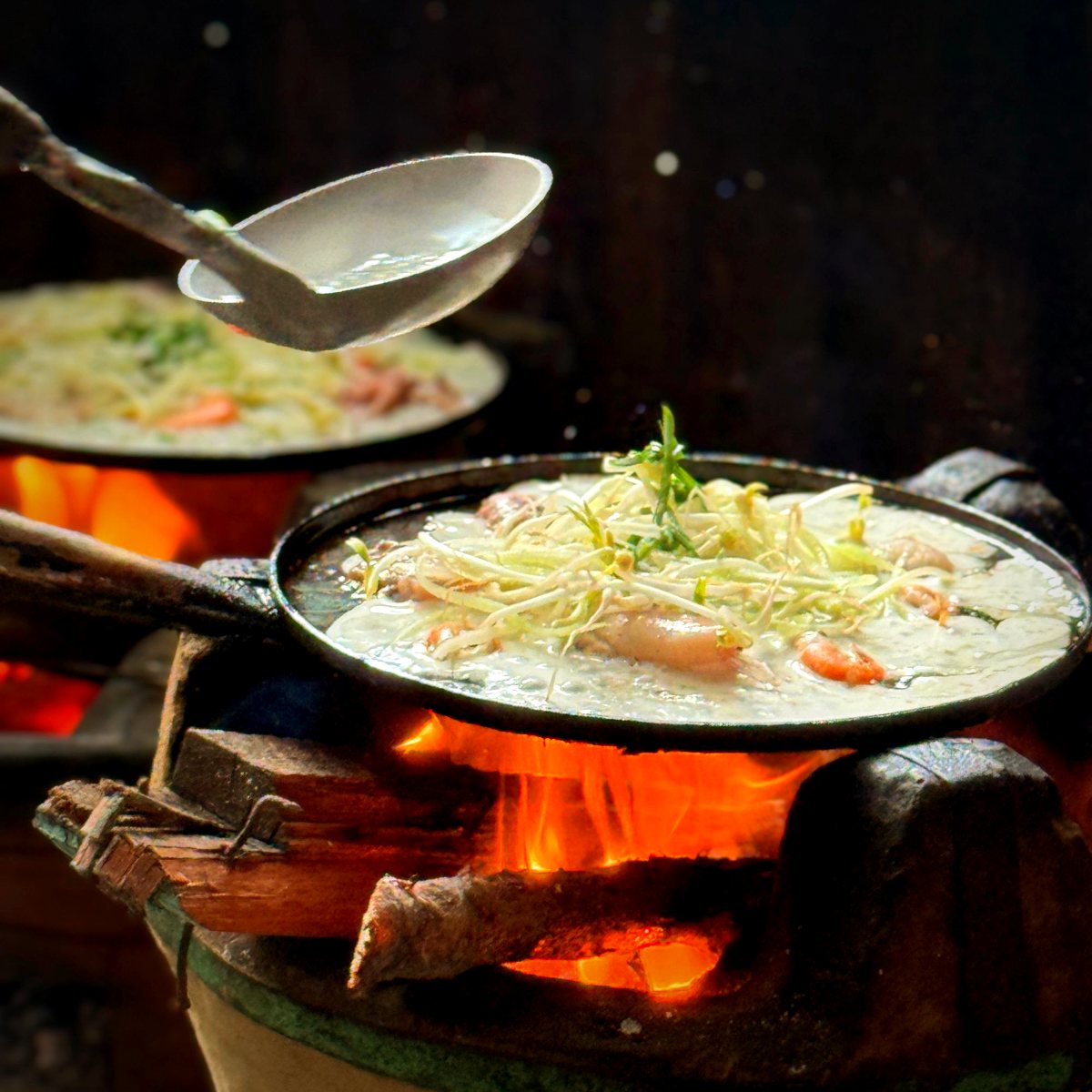 Bánh xèo có tôm đang đổ trên chảo, bếp củi đỏ lửa